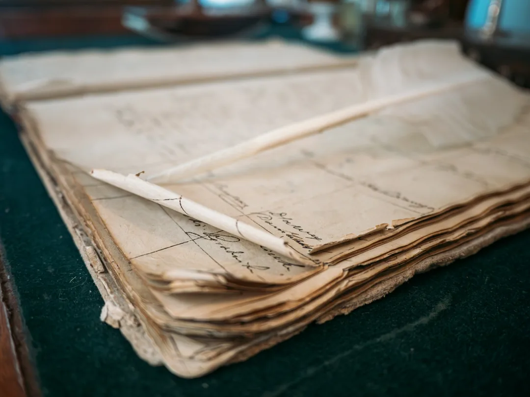 Libro manuscrito abierto sobre una mesa, con hojas de papel envejecido y anotaciones a tinta